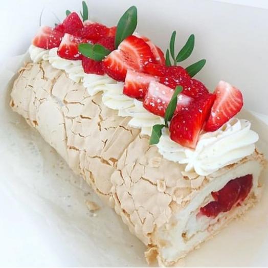 Rollo de merengue con relleno de bayas, decorado con crema y bayas frescas